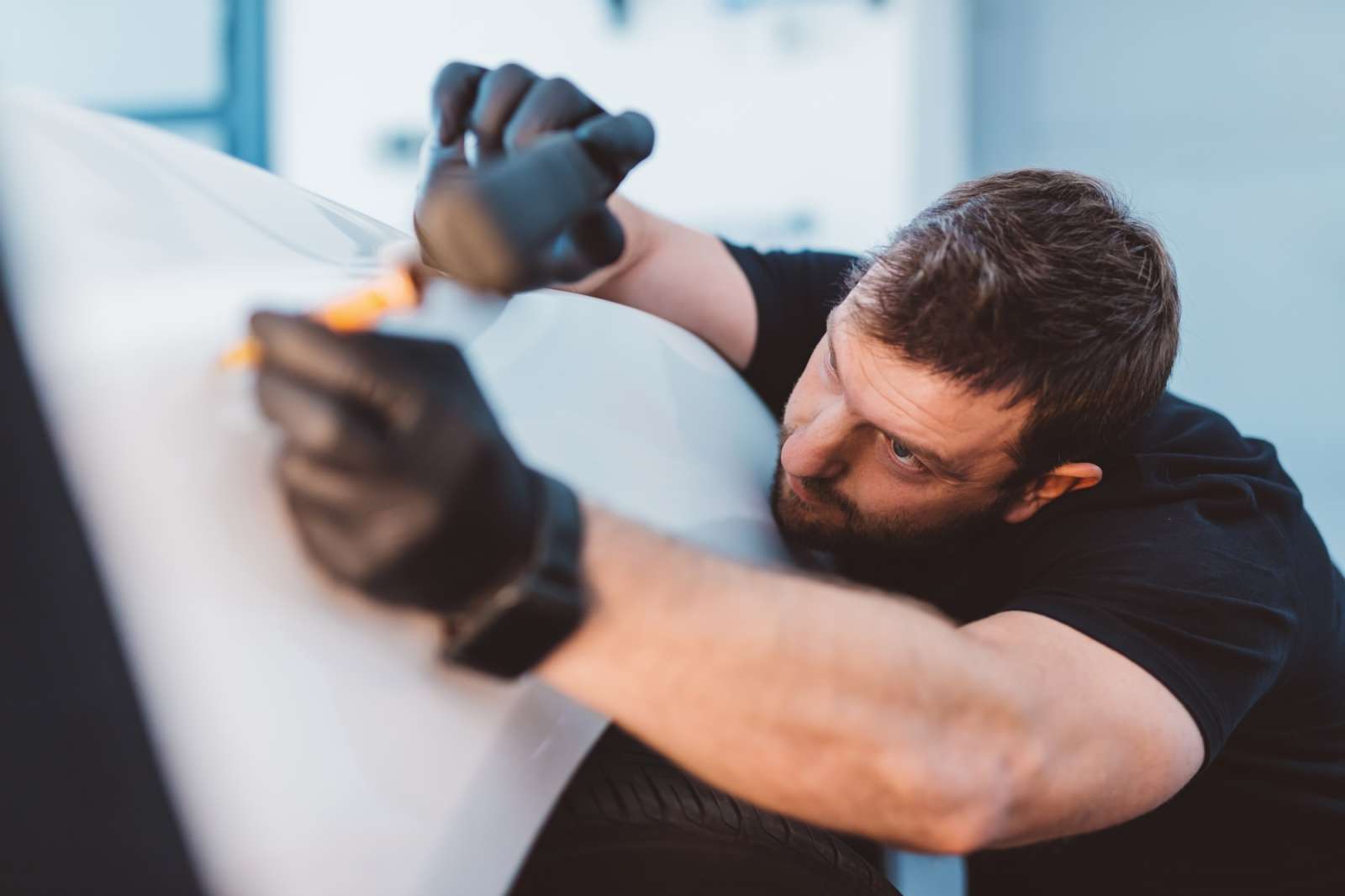 Car mechanic working to remove dent in workshop.